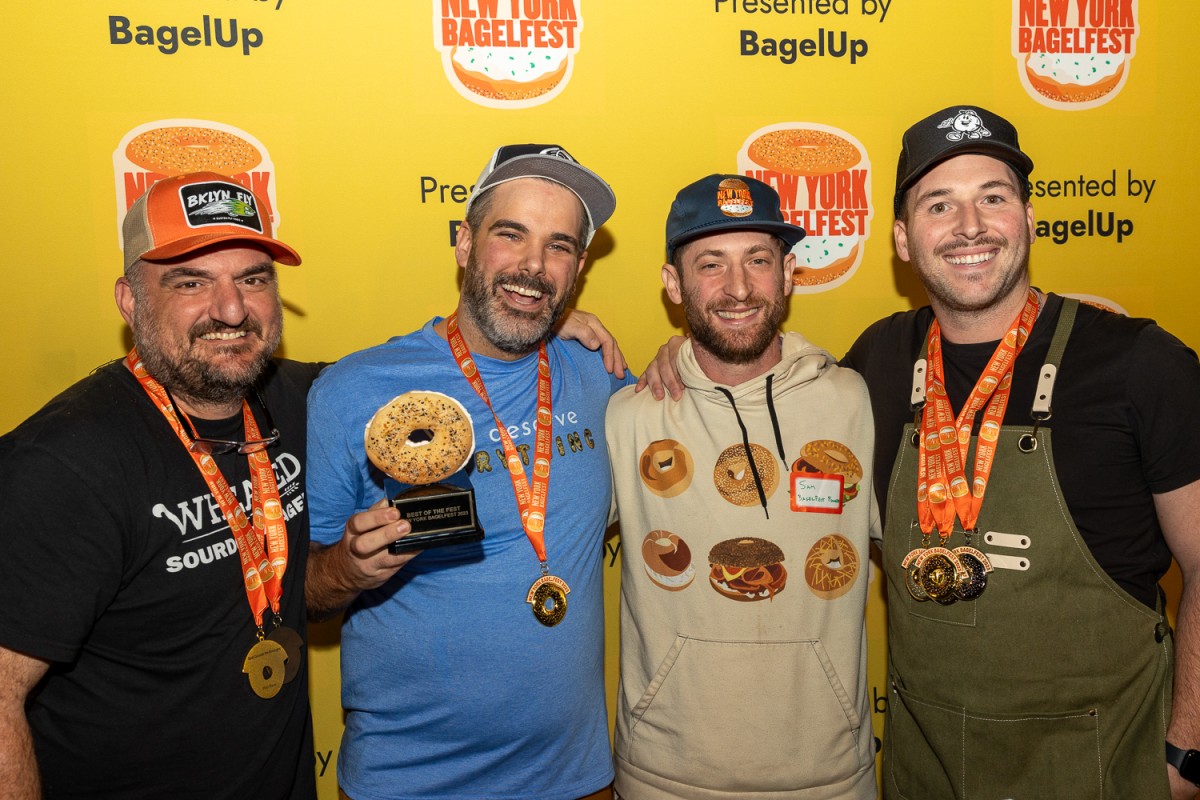 From left to right: A representative from Wheated in a black shirt, a representative from Olmo in a blue shirt, Sam Silverman the founder of New York BagelFest in a beige pullover hoodie, and a representative from O’Bagel in a black shirt and black baseball cap with a green apron.