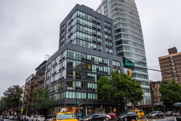 New York University’s Sixth Street residence hall, a tall glass building, seen from a busy street.