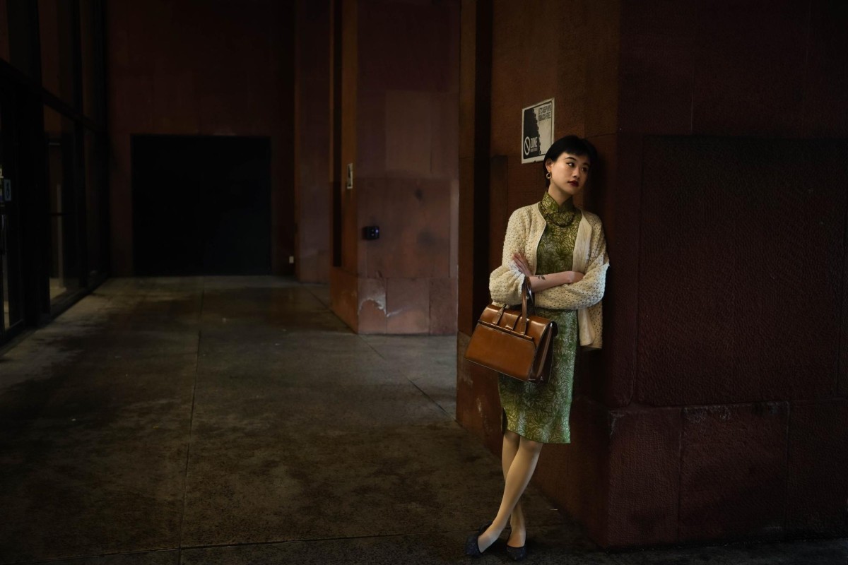 Guo leans on a pillar in front of Bobst Library, wearing a green Cheongsam dress.