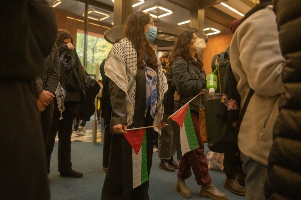 Two participants hold Palestinian flags in front of the entrances on the first floor of the Bobst Library.
