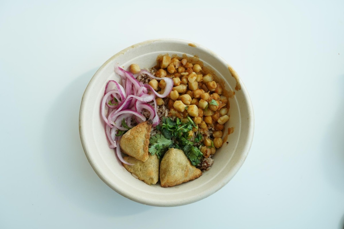 A bowl containing onions, chickpea stew, cilantro and samosas.