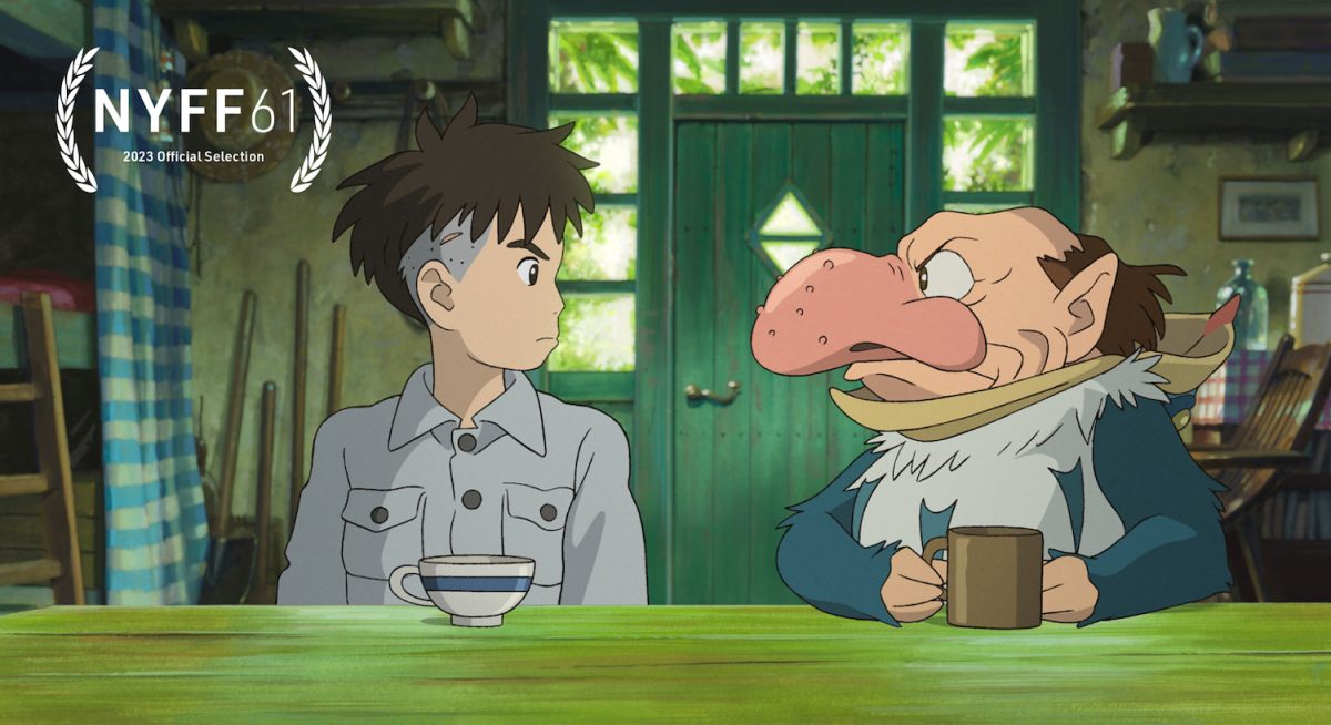 This is a still from an animated film. It features a boy and a man, with a nose resembling a beak, looking at each other. They are sitting by a green table with tea cups in front of them.