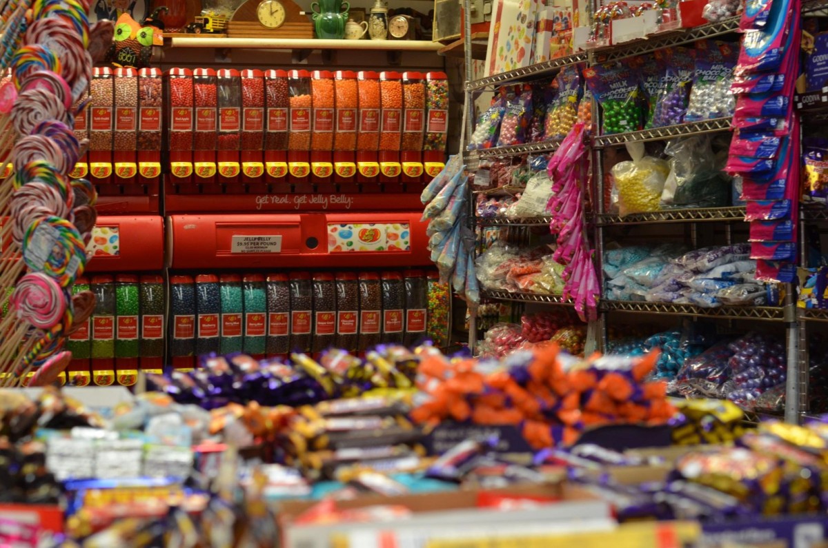 A store filled with shelves of candy, jelly bean dispensers, and lollipop stands.