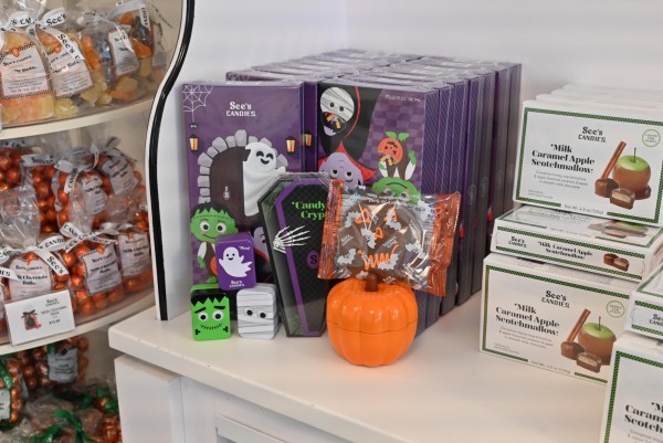 A shelf displaying various boxes of candies including a display of halloween candy boxes decorated with different Halloween monsters.