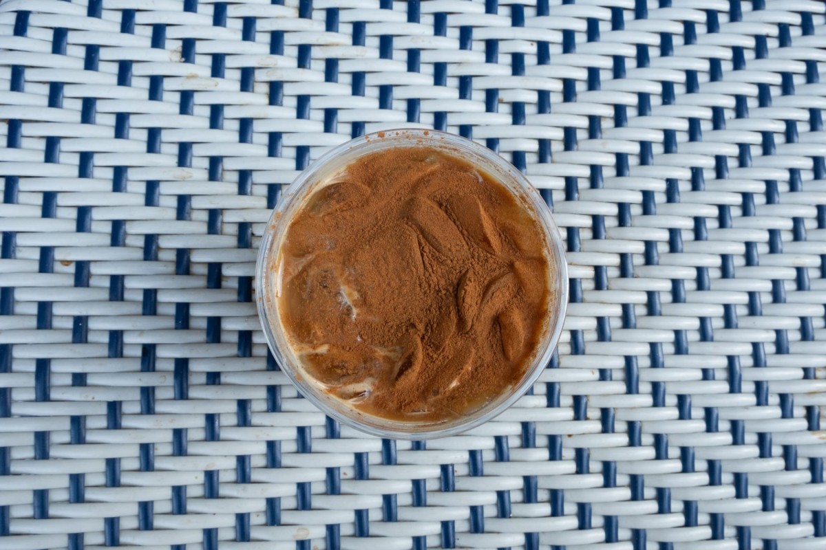 A birds-eye view of a pumpkin spice latte on a white wicker table.
