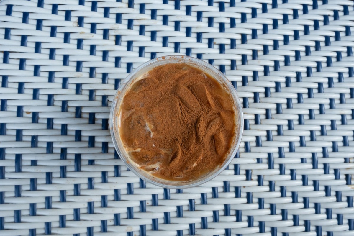 A bird's-eye view of a pumpkin spice latte on a white wicker table.