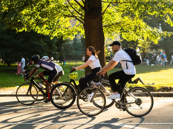 People bike on a sunny evening on the street at Central Park.