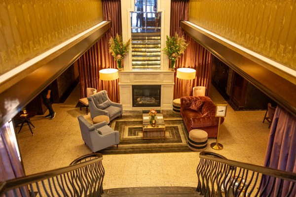 Marble staircase leading down to a red couch and gray seats around a small coffee table. Soft ambient lighting illuminates the walls.