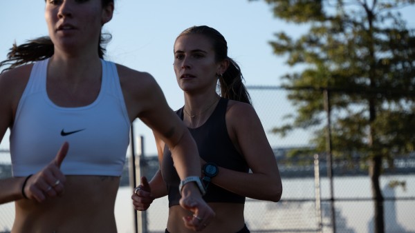 Two people are working out. They both have ponytails and are wearing sports bras.