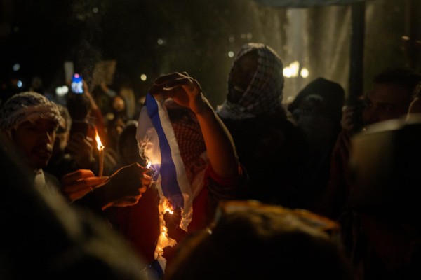 Pro-Palestine protestors burn the Israeli flag.