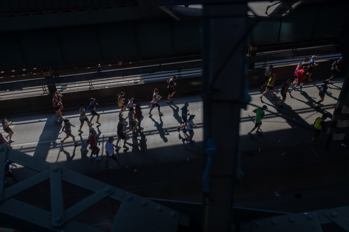 People in various colored outfits run across the Ed Koch Queensboro Bridge into Manhattan from Queens.