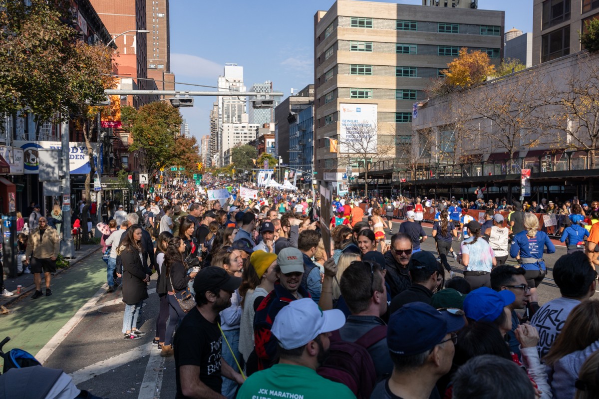 A large crowd of people watch the runners pass by along First Avenue in Manhattan.