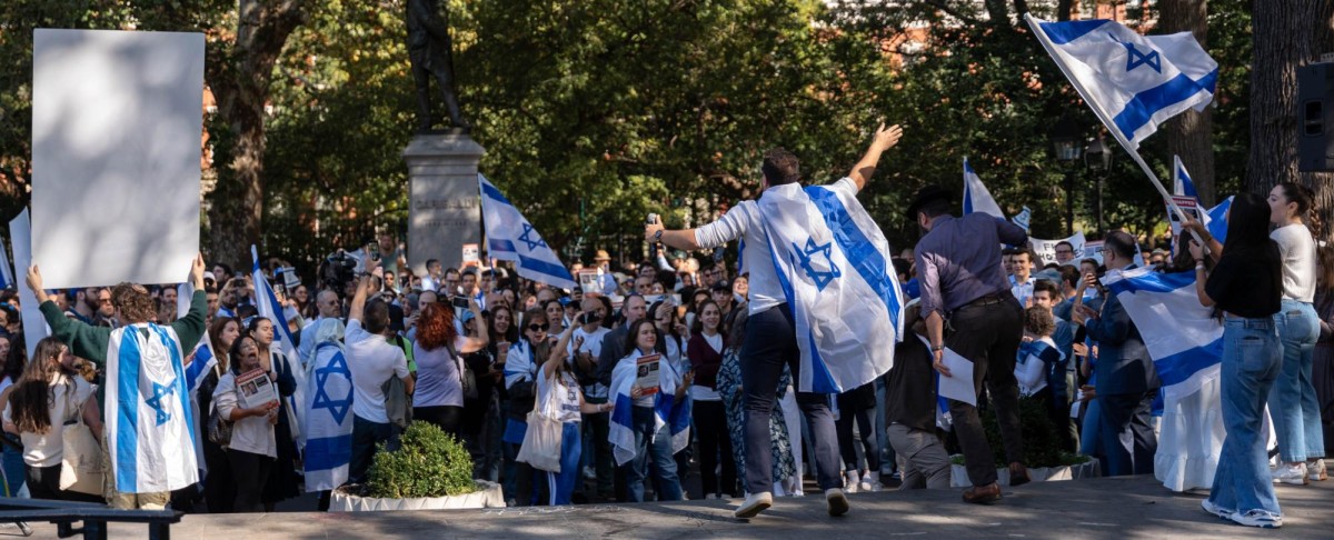 A group of pro-Israeli protesters holds signs and Israeli flags in front of the Garibaldi statue in Washington Square Park.