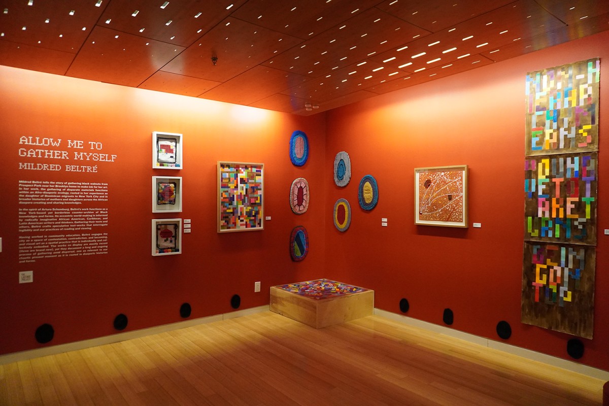 A collection of artwork is hung up in front of an orange background, with the exhibition name “ALLOW ME TO GATHER MYSELF” and description on the left.