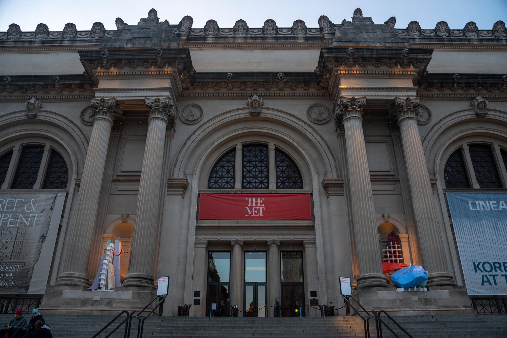 The facade of The Metropolitan Museum of Art featuring a red banner which reads “THE MET.”