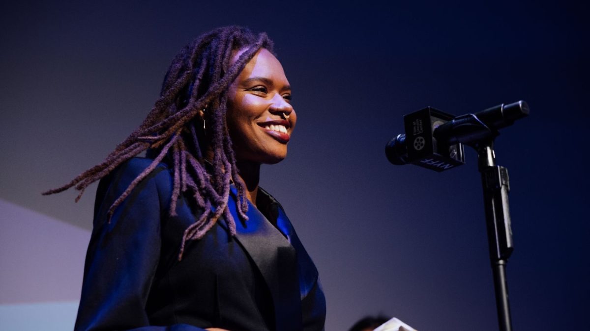 A girl smiling in a black shirt in front of a mic.