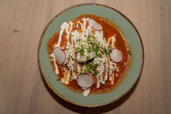 A pale blue plate with red sauce drizzled with a white sauce and garnish.