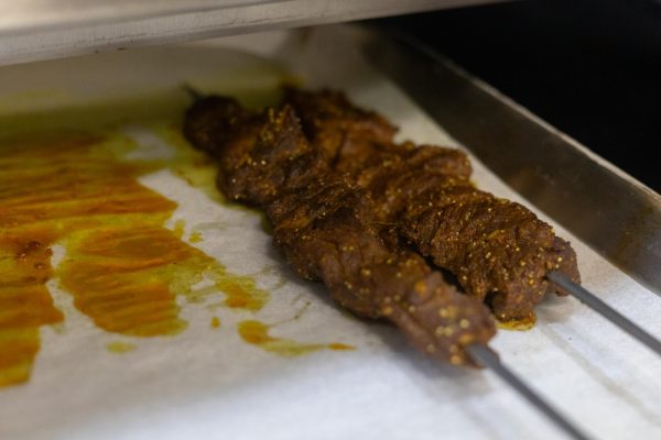 Two flame-grilled and marinated beef skewers on a pan.