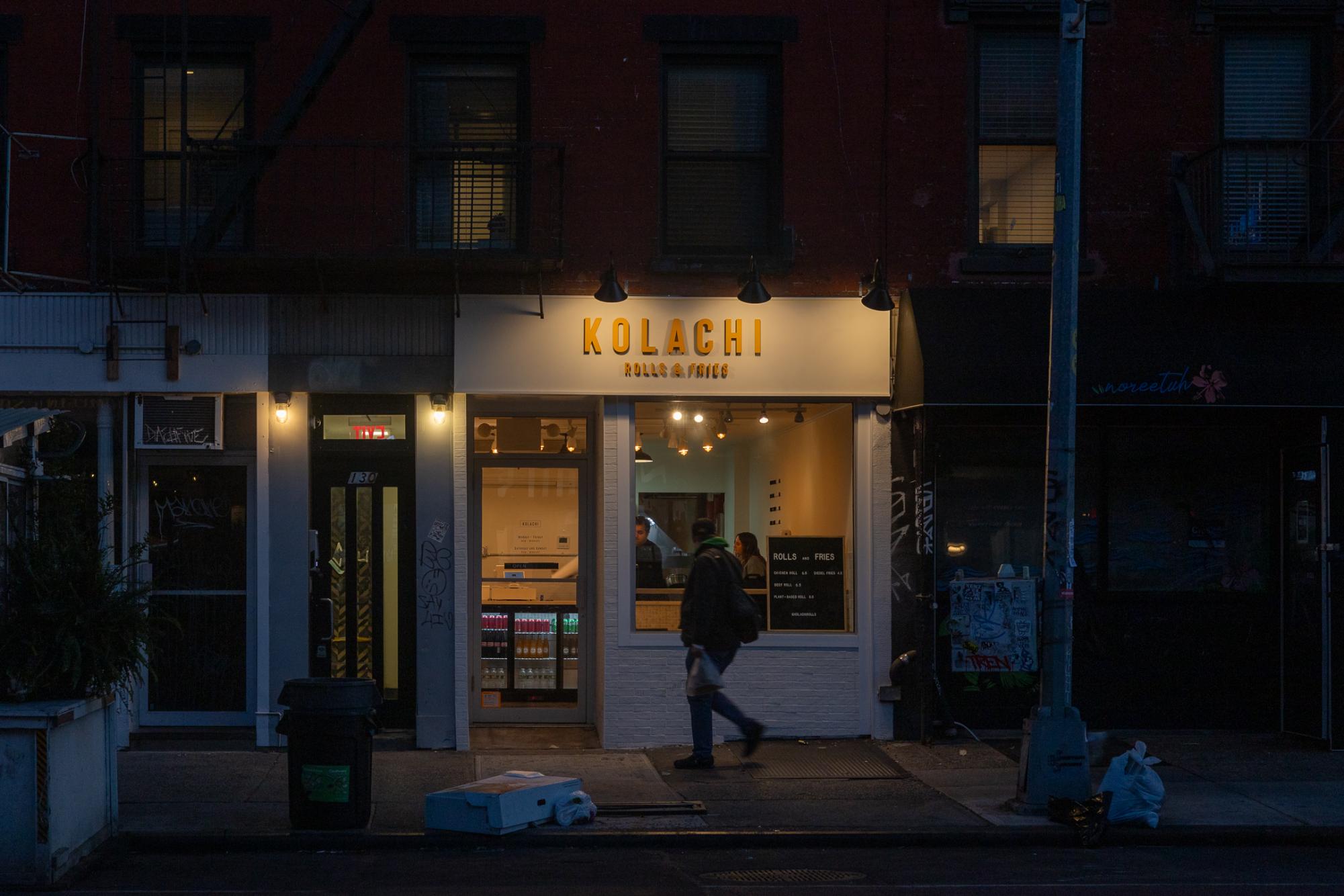 The storefront of the restaurant which has “KOLACHI” and “ROLLS AND FRIES,” written in yellow text.