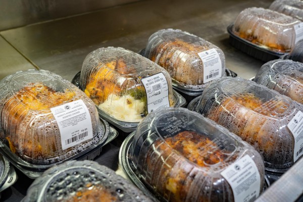 Two rows of rotisserie chicken placed on a shelf in a supermarket.