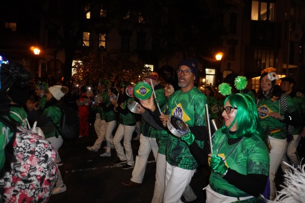 A Samba band in green shirts playing tamborines.