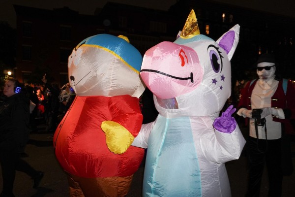 A person in an inflatable unicorn costume with another person in an inflatable costume dressed as Eric from South Park that has a red jacket and blue hat with a yellow pompom.
