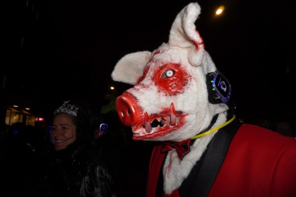 A bloody white pig with headphones, a red blazer and a red bow tie.