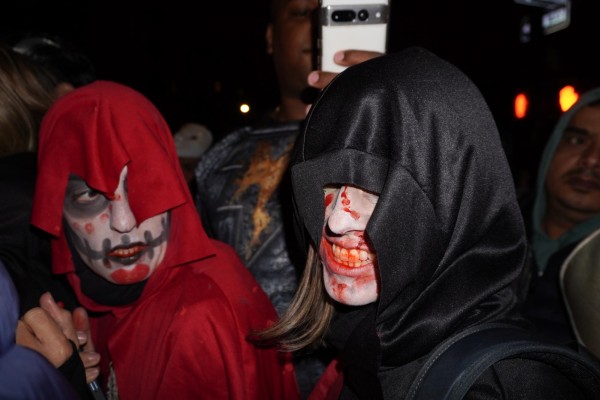 A person in ghost makeup with a red hooded cape and another person with a bloody face and a black hooded cape.