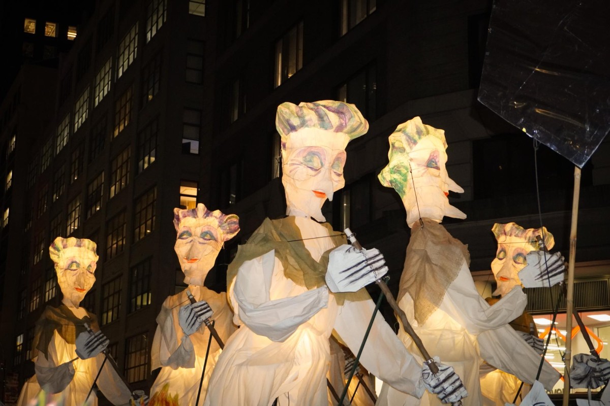 Inflatable glowing grandma puppets holding brooms.