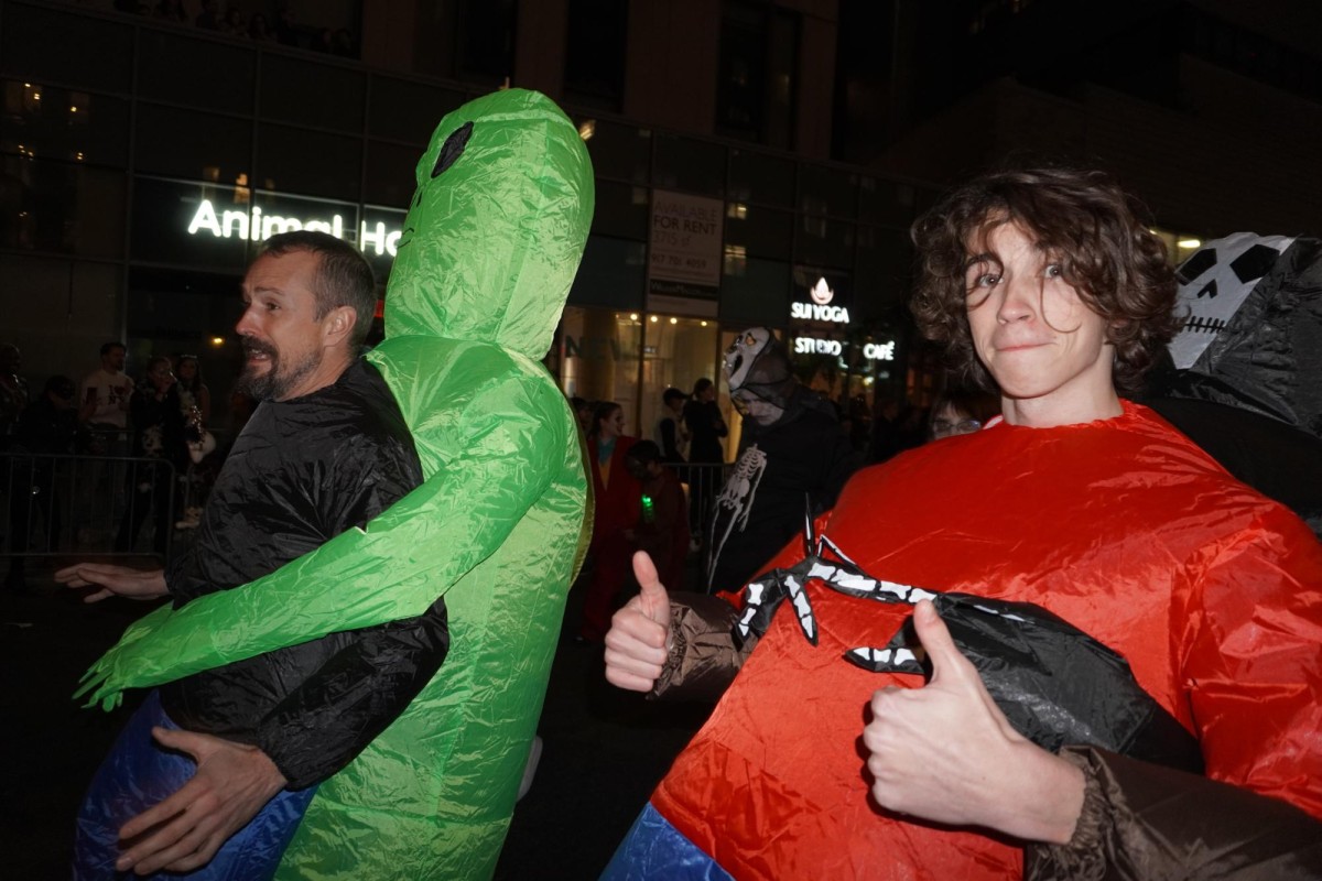 A person dressed up in an inflatable alien costume and another person in an inflatable red costume.
