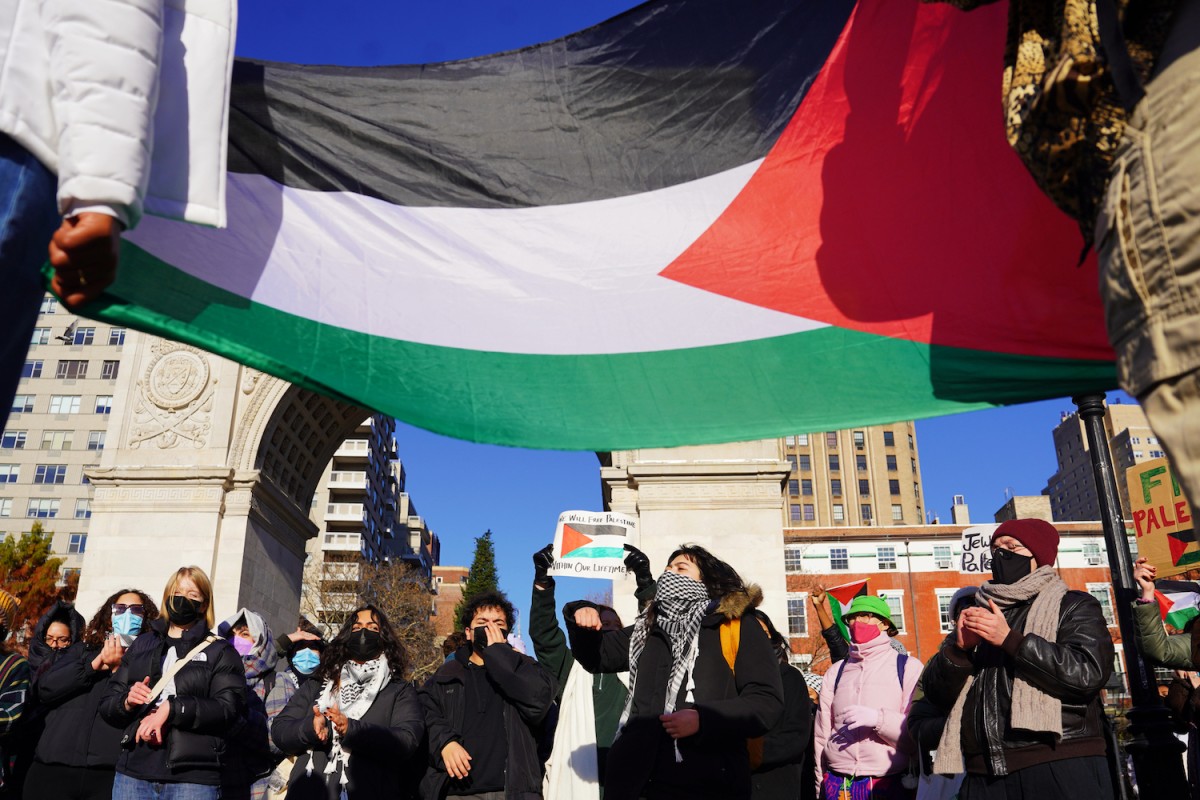 People+are+standing+in+front+of+the+Washington+Square+Arch+beneath+a+large+Palestinian+flag.