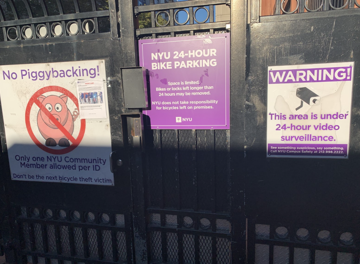 Three signs are posted on a black metal fence. The signs are purple and white. one of the signs says “N.Y.U. 24-HOUR BIKE PARKING.”