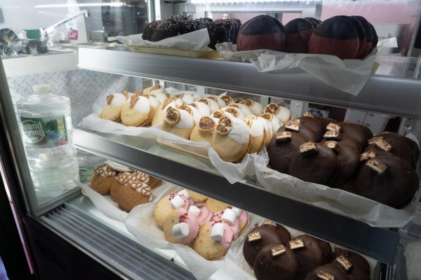 Various desserts are displayed in wrappers on three layers of shelves inside a refrigerated case.