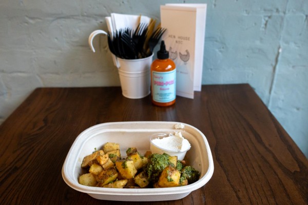 Cilantro potatoes with a side of garlic sauce in a paper container.