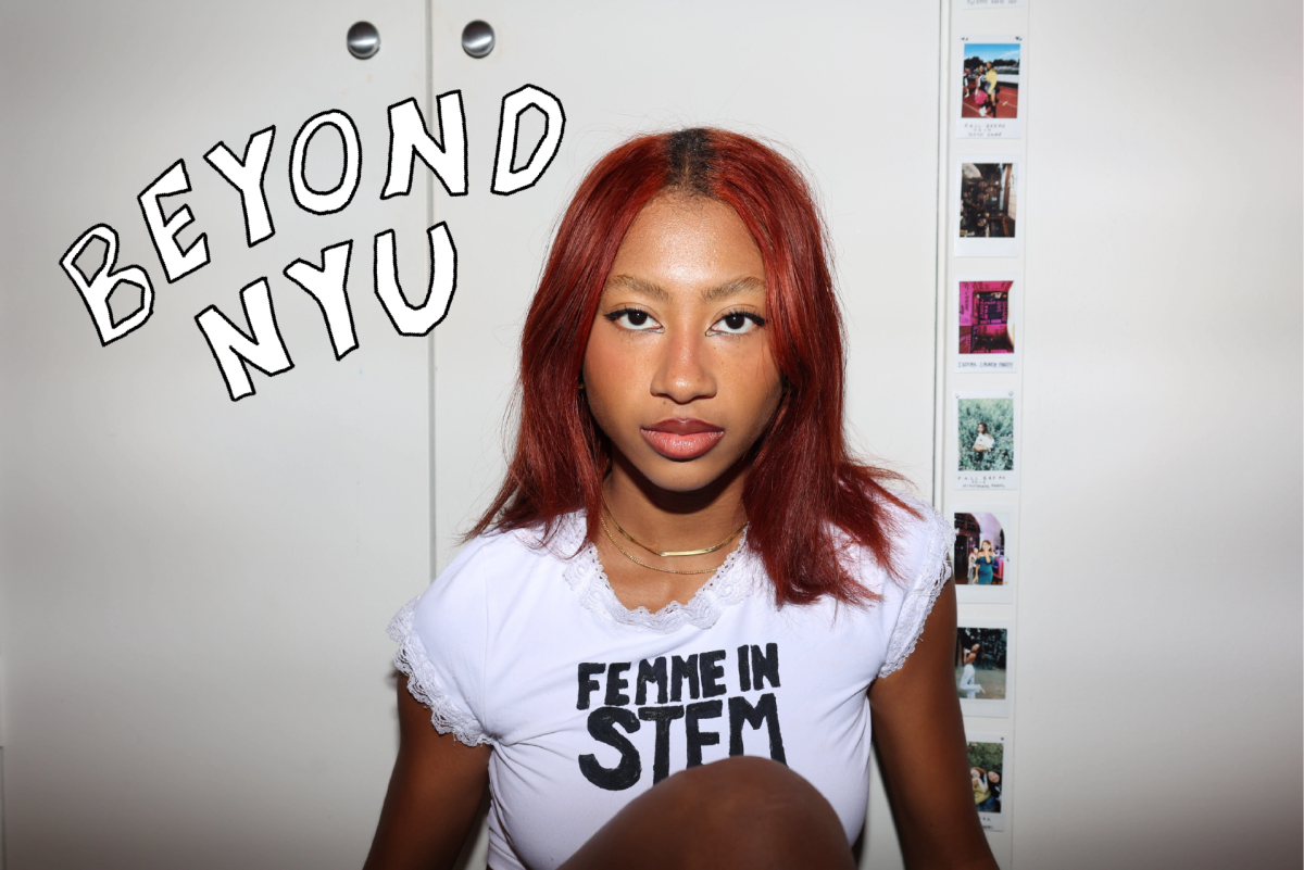 A person with red hair is sitting in front of a white wall. She is wearing a white shirt that says, “FEMME IN STEM.” There are Polaroid photos stuck to the wall to her right. On top of the image are two white hand-drawn words with black borders that say “BEYOND N.Y.U.”