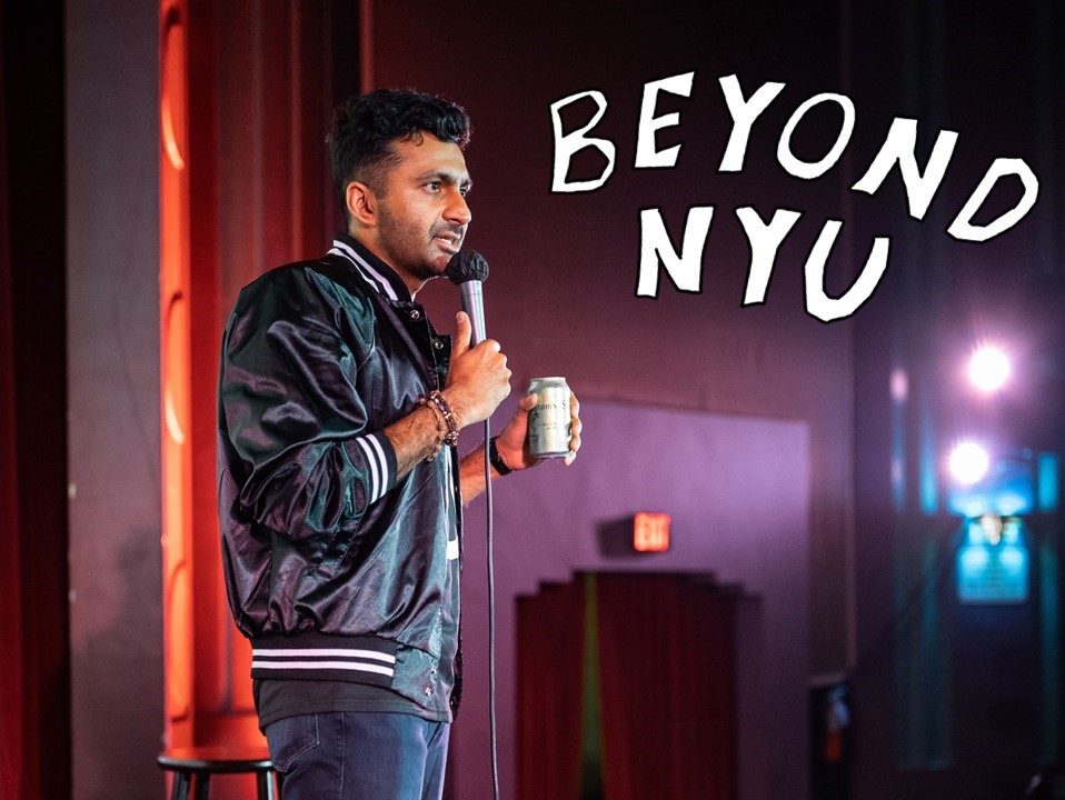 A person wearing a black leather jacket stands on a stage while holding a microphone in his right hand and a can in his left hand. On top of the image are the words “BEYOND N.Y.U.”
