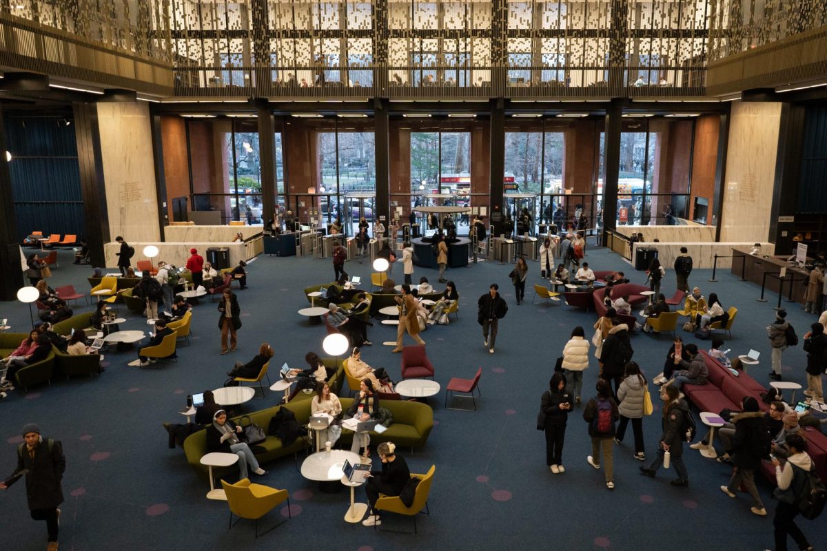 An+aerial+view+of+the+lobby+of+Bobst+Library+crowded+with+people+both+walking+and+sitting+on+green+and+red+couches.