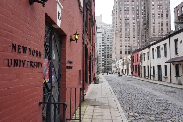 A side view of the entrance to the La Maison Française. The words “New York University” and “La Maison Francaise” are displayed on the red brick walls on either side of the door in black letters.