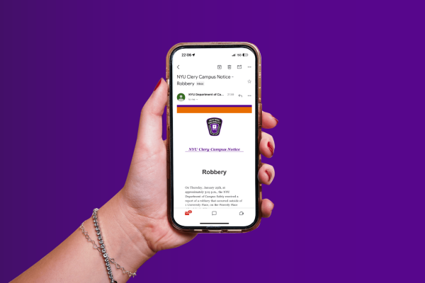 A hand holding an iPhone with an email from NYU Campus Safety reporting a robbery incident displayed on it placed in front of a purple background.