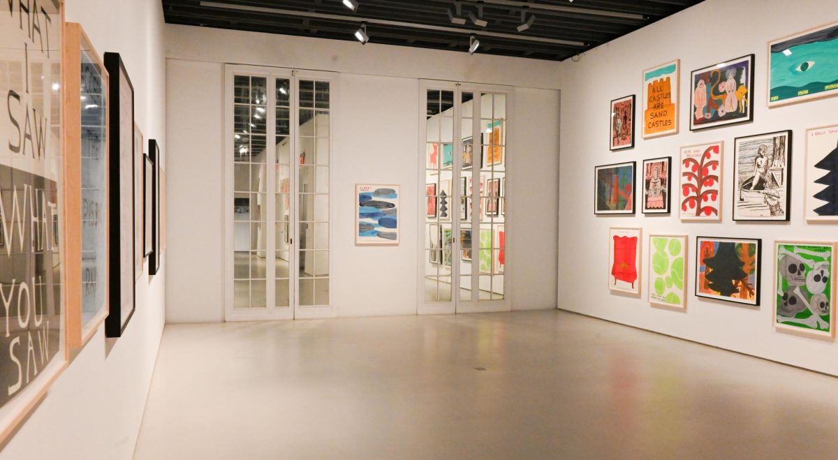 A large room with white walls and floors has a variety of framed paintings on display in a grid.