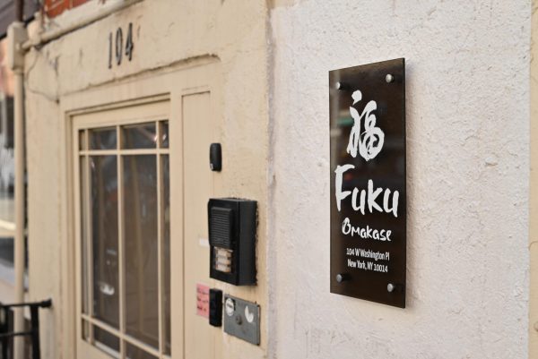 A beige wall and door with a black sign that says “Fuku Omakase” and has a kanji character on it.