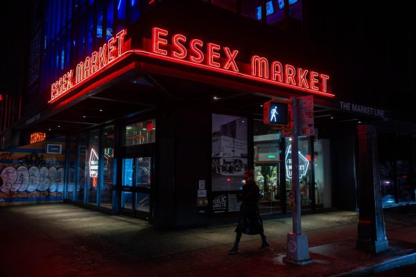 The exterior of a marketplace where two neon light signs that say “ESSEX MARKET” are placed above the entrance.