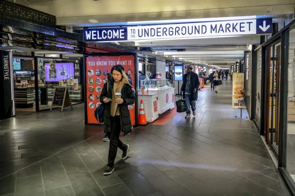 People walking through a marketplace with rows of restaurants and vendors. A lit sign saying “WELCOME TO THE UNDERGROUND MARKET” hangs from the ceiling.