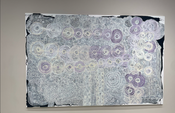 A painting with white and light purple circular patterns is on a white wall.