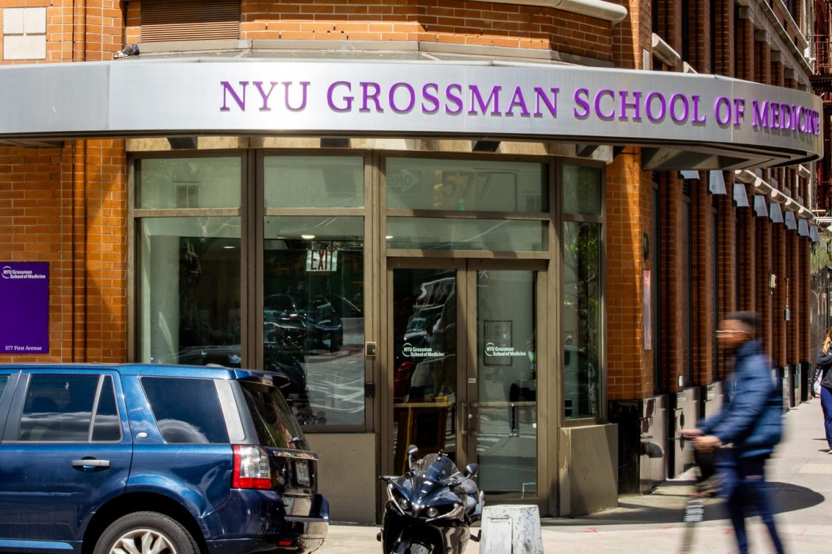 N.Y.U. Grossman School of Medicine building. It is a red brick building. People are walking outside the building and a large sign with “NYU Grossman School of Medicine is in the front.