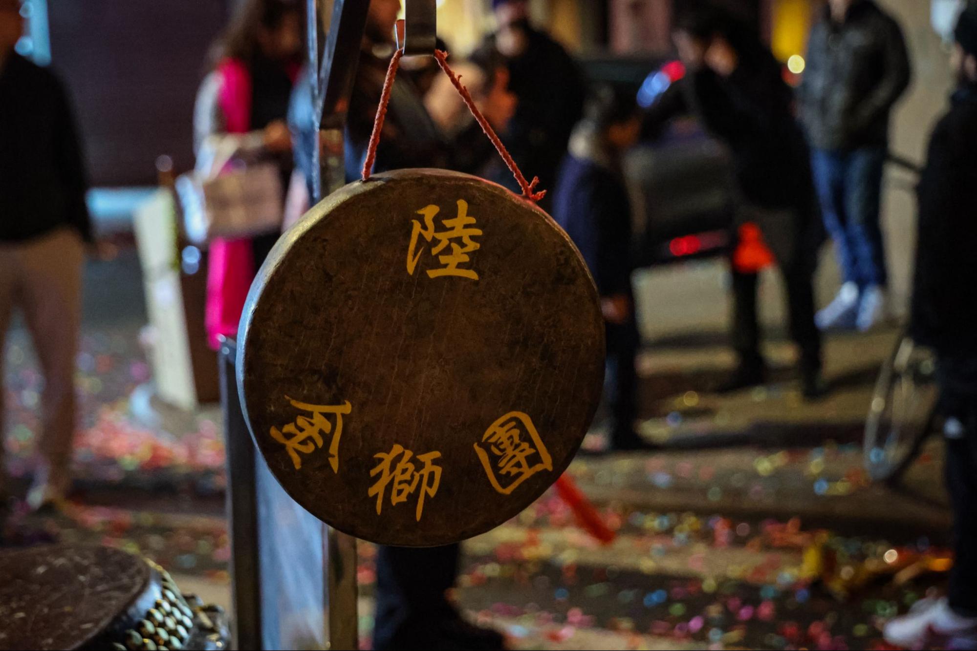 A gong with yellow Chinese characters hangs from a red string.