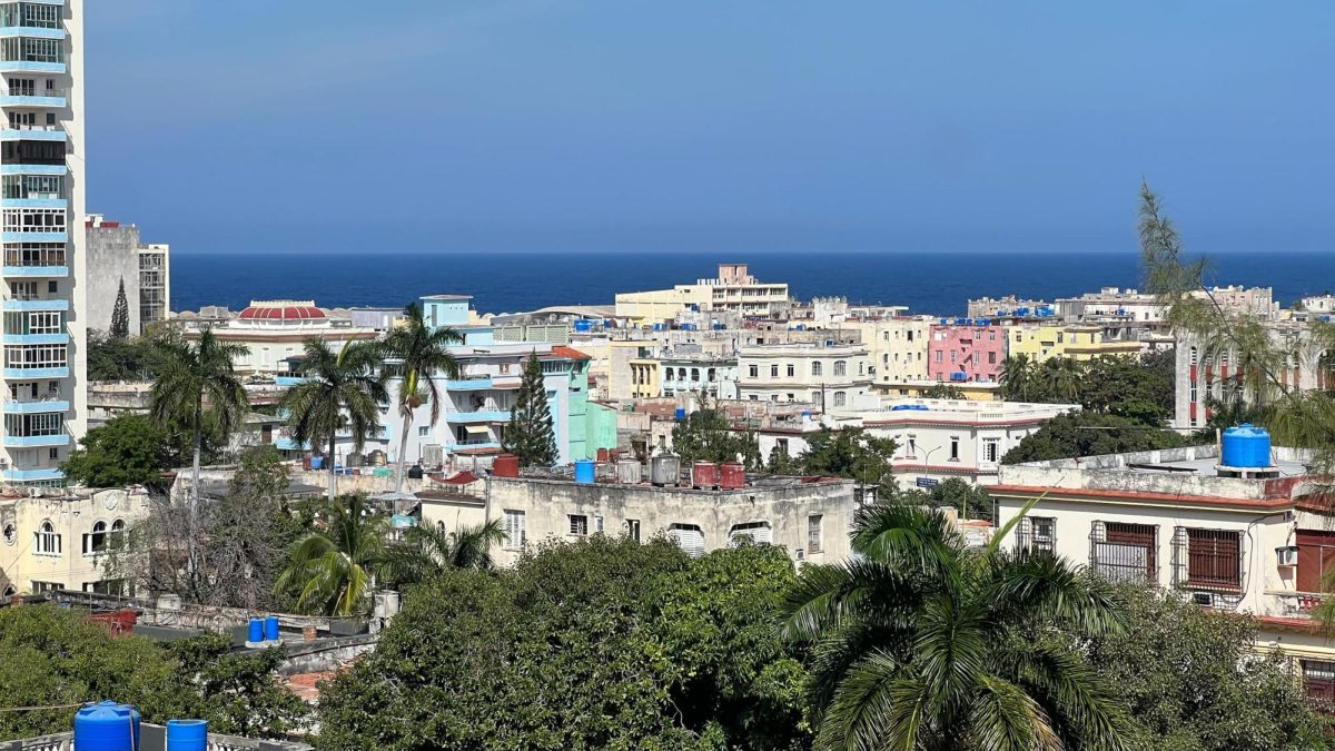 An aerial view of Havana, where a group of short, colorful buildings are located in front of the Caribbean Sea.
