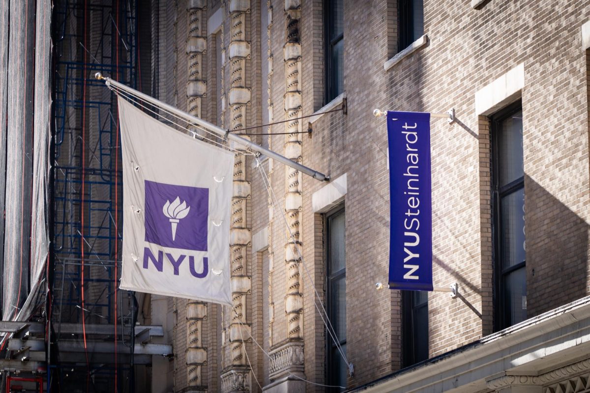 A+white+and+purple+N.Y.U.+flag+and+a+purple+banner+that+says+N.Y.U.+Steinhardt+is+placed+side+by+side+on+a+building+wall.