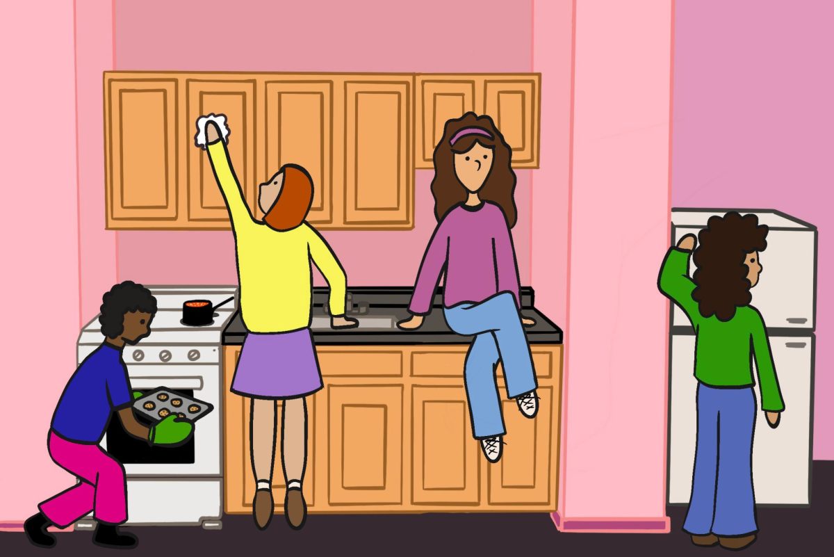 Four girls occupy a dorm room kitchen with a coffee machine on the left, a dish rack next to it, a sink in the middle and an oven with food inside it on the right.