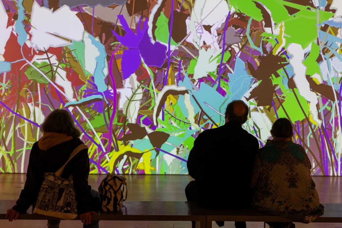 Three+people+sitting+in+front+of+a+screen+with+bright%2C+colorful+strokes.